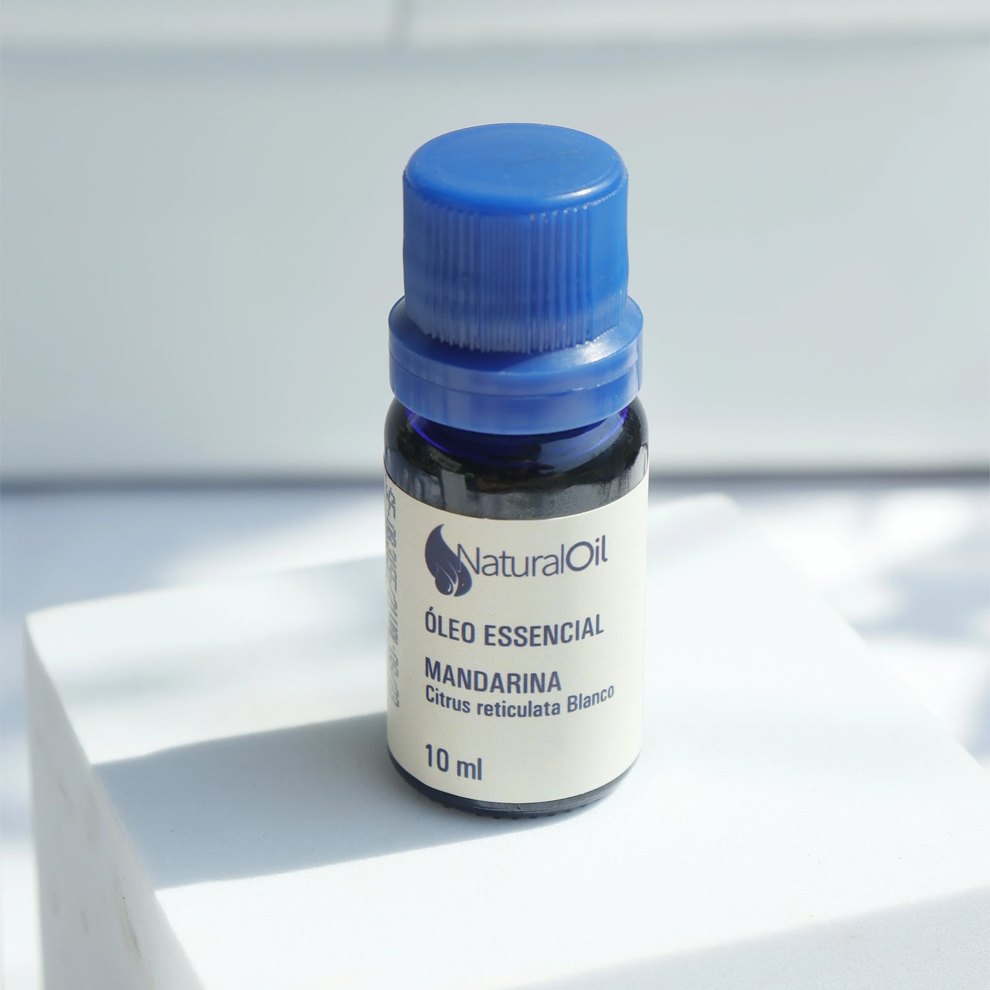 Frasco de óleo essencial de mandarina 10ml para aromaterapia em fundo claro.