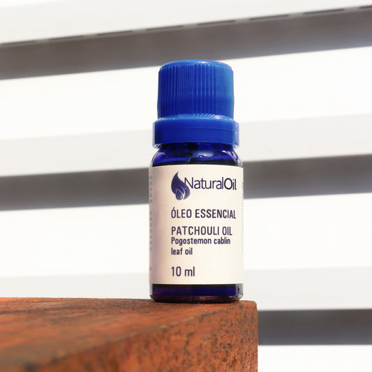 Frasco de óleo essencial de patchouli 10ml sobre superfície de madeira, fundo claro