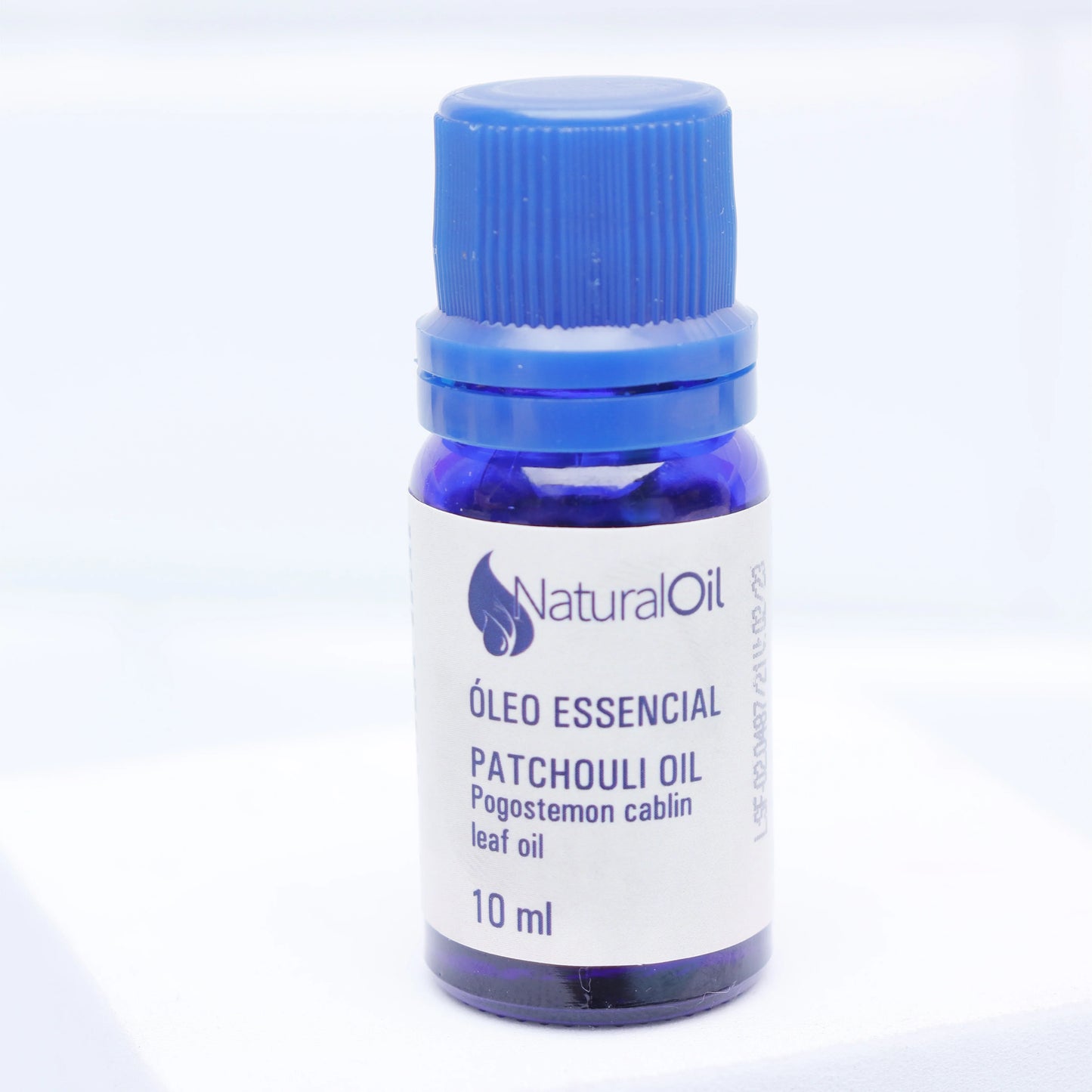 Frasco de óleo essencial de patchouli 10ml para aromaterapia, tampa azul, fundo claro.