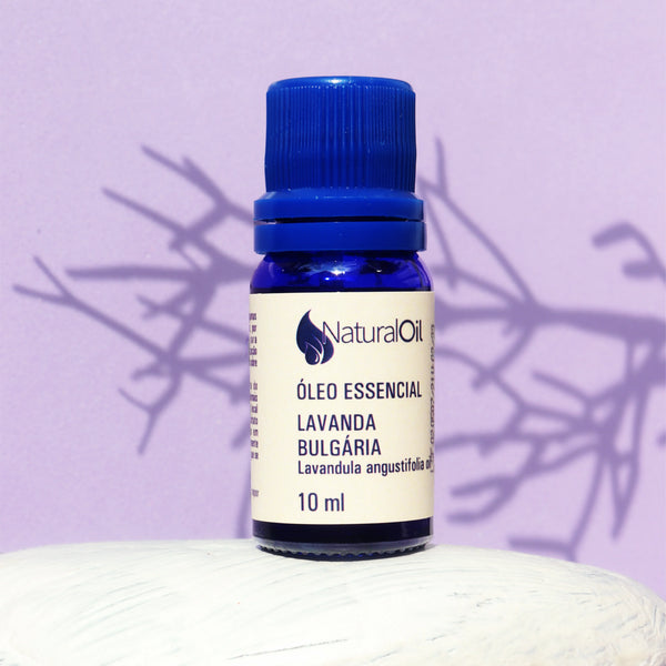 Frasco de óleo essencial de lavanda búlgara 10ml com tampa azul, sobre fundo lilás.